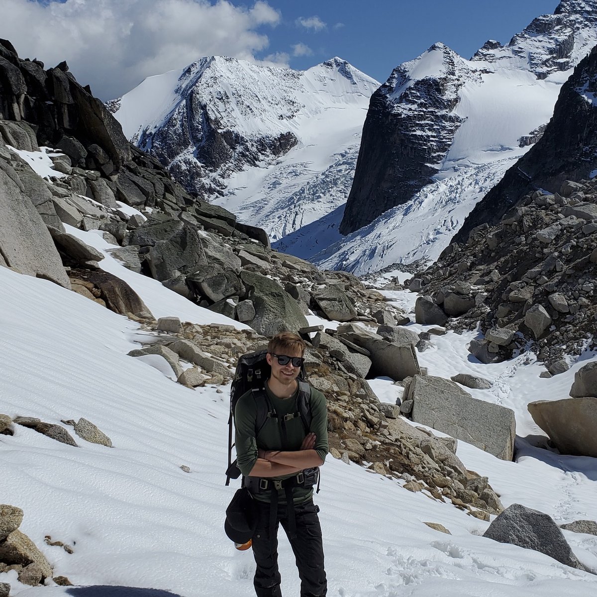 Nikolay standing in the snow with mountains behind him